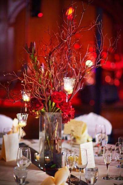 A festive table setting with a centerpiece of red roses and branches with small hanging candles at The Stanley Hotel