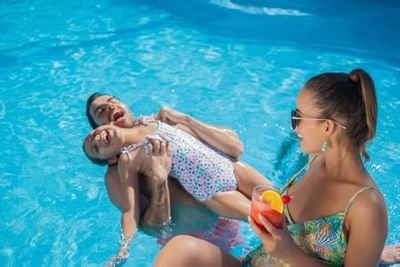 Family enjoying pool time with mother and children playing in crystal blue water at Playa Los Arcos Puerto Vallarta 2023