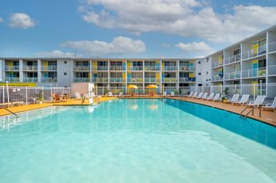 Outdoor pool area surrounded by colorful hotel balconies and lounge chairs at Kokomo Suites