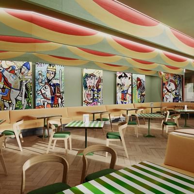 Buntes Restaurant mit farbenfrohen Wandgemälden, gestreiften Tischen und Holzbänken.