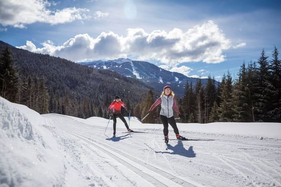 Skiers on snowy pathway with a scenic view near Blackcomb Springs Suites