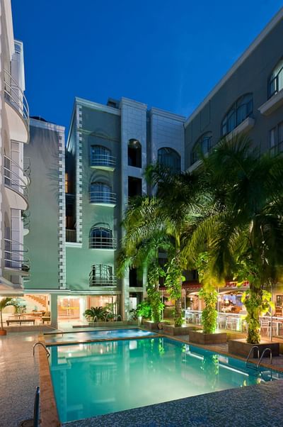 Foto nocturna de la piscina y el patio del Hotel Country International, en la que destacan las amplias habitaciones del hotel de Barranquilla.