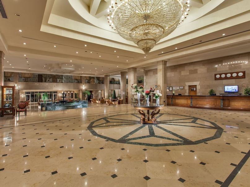 Elegant lobby with a large chandelier, marble floors, floral centerpiece & reception desk at Pickalbatros Golf Beach Resort