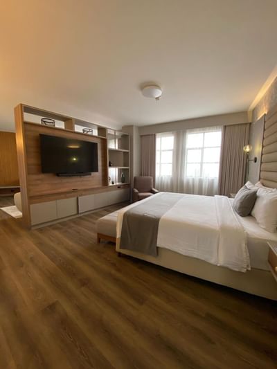 Suite Carlton featuring a large bed, TV unit, seating area, and abundant natural light from windows at Dann Carlton Cali