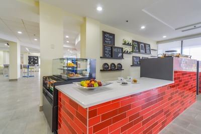 Counter with bowl of fresh fruit & dining area in Coffee Bar at St. Louis Airport Hotel