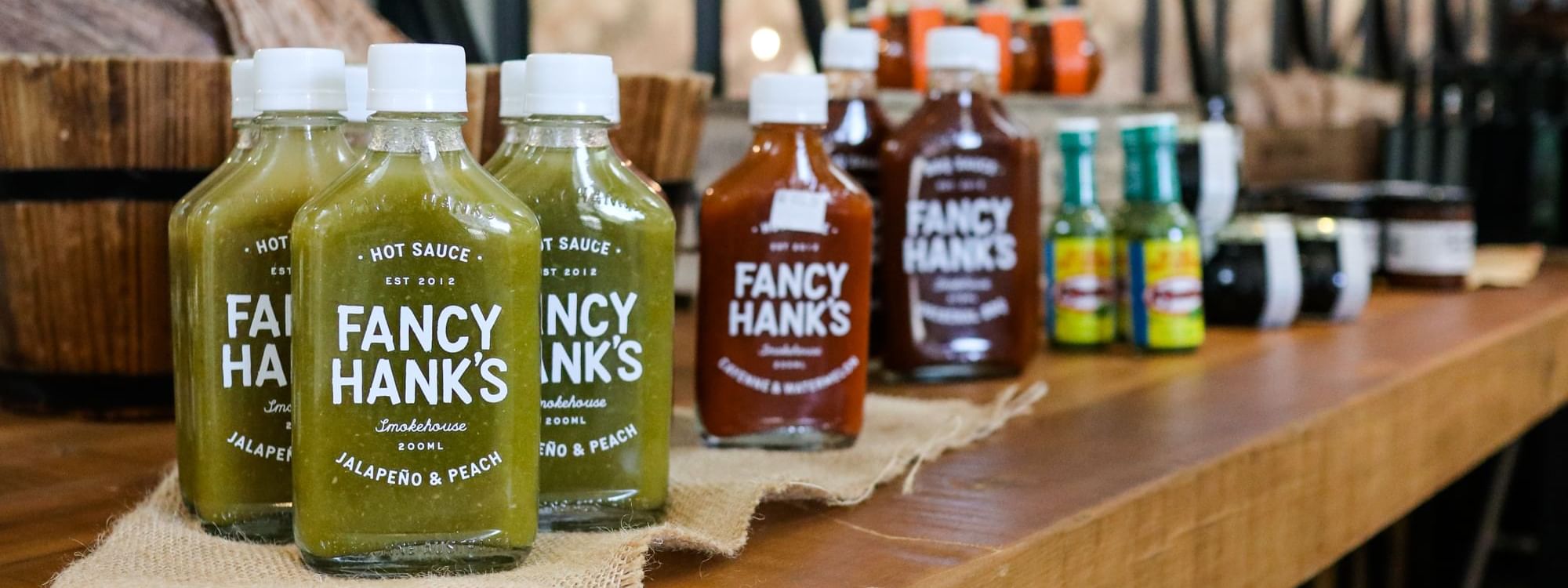 Fancy Hank's hot sauces lined up on a wooden counter in The Marke Kitchen at Novotel Sydney International Airport