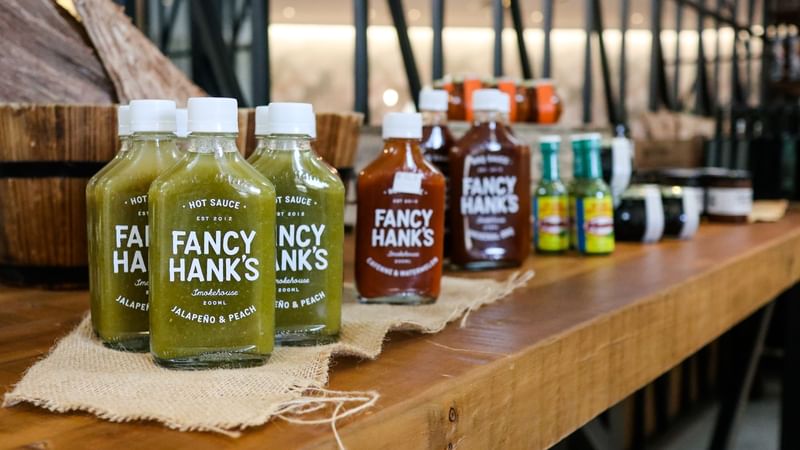 Fancy Hank's hot sauces lined up on a wooden counter in The Marke Kitchen at Novotel Sydney International Airport