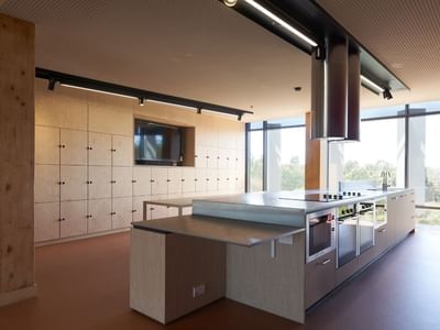 Modern kitchen with large island, appliances, and wooden cabinets in La Trobe University apartments.