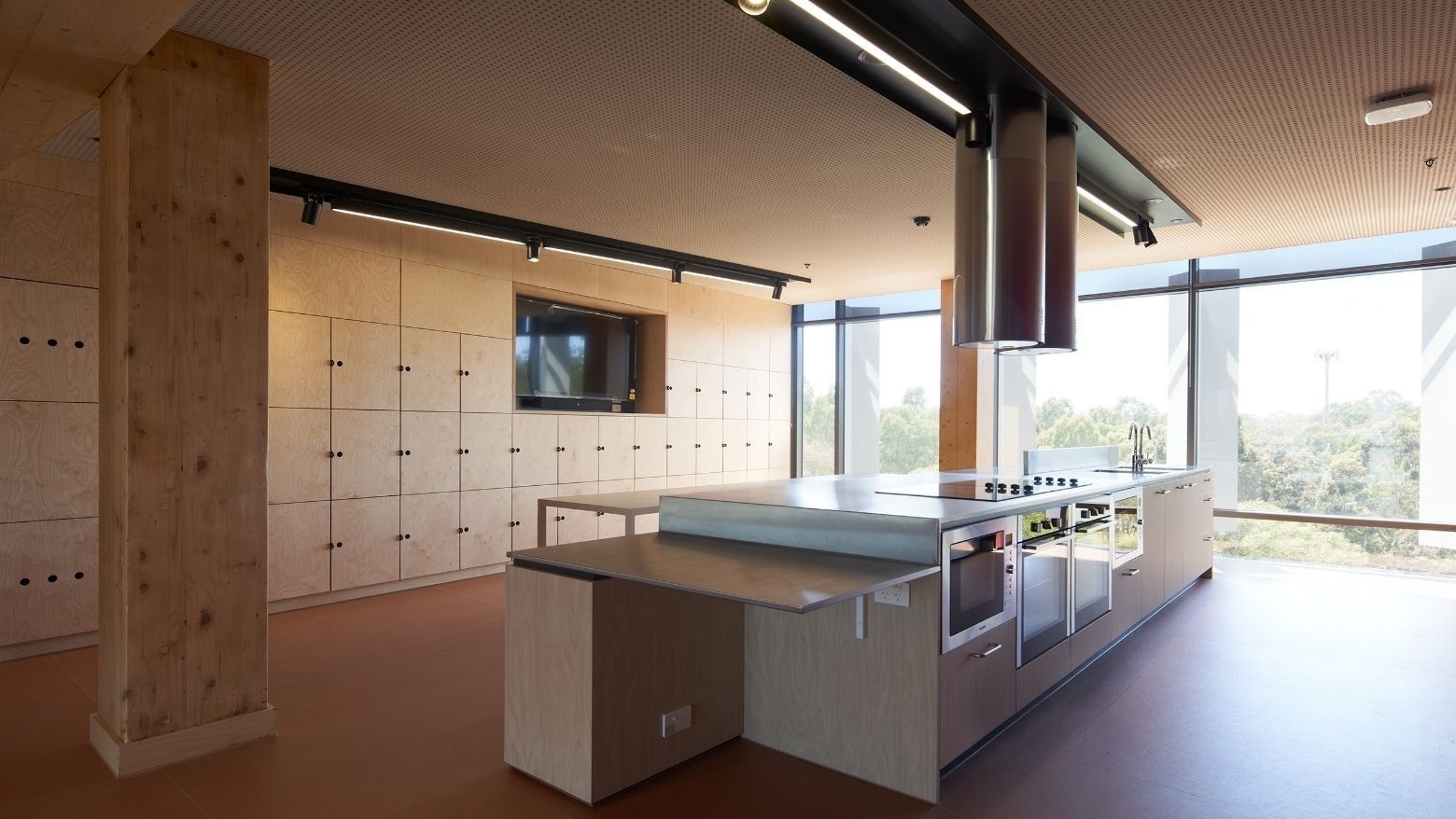 Modern kitchen with large island, appliances, and wooden cabinets in La Trobe University apartments.
