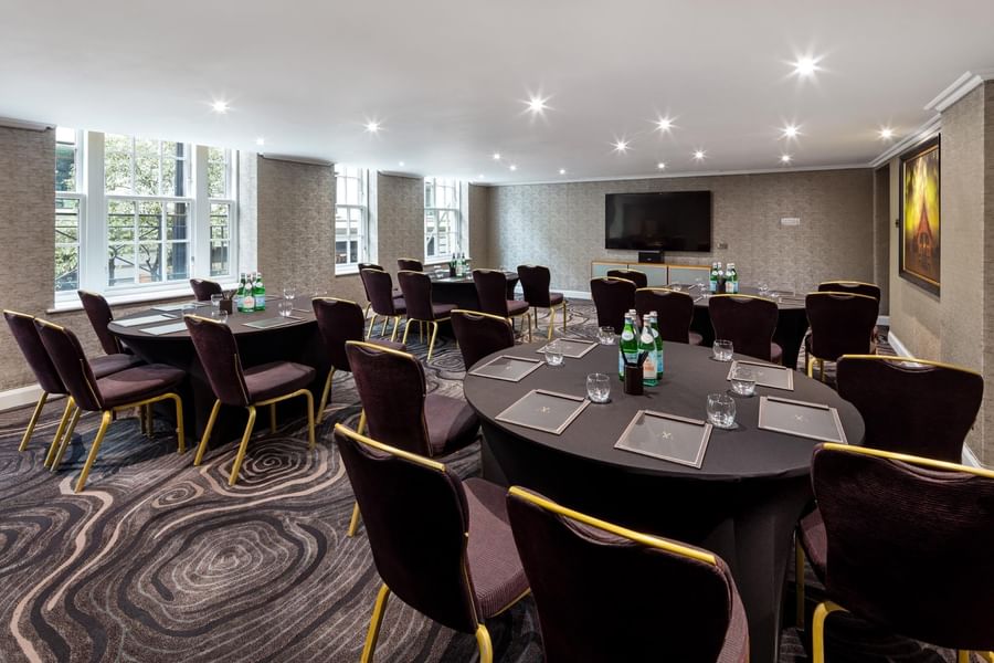Cabaret-style meeting room with round tables and chairs arranged for small meetings at The May Fair Hotel