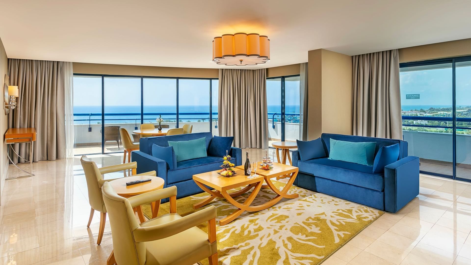 Spacious living room with two blue sofas, coffee tables on a patterned rug in Colonel Suite at Titanic Deluxe Lara