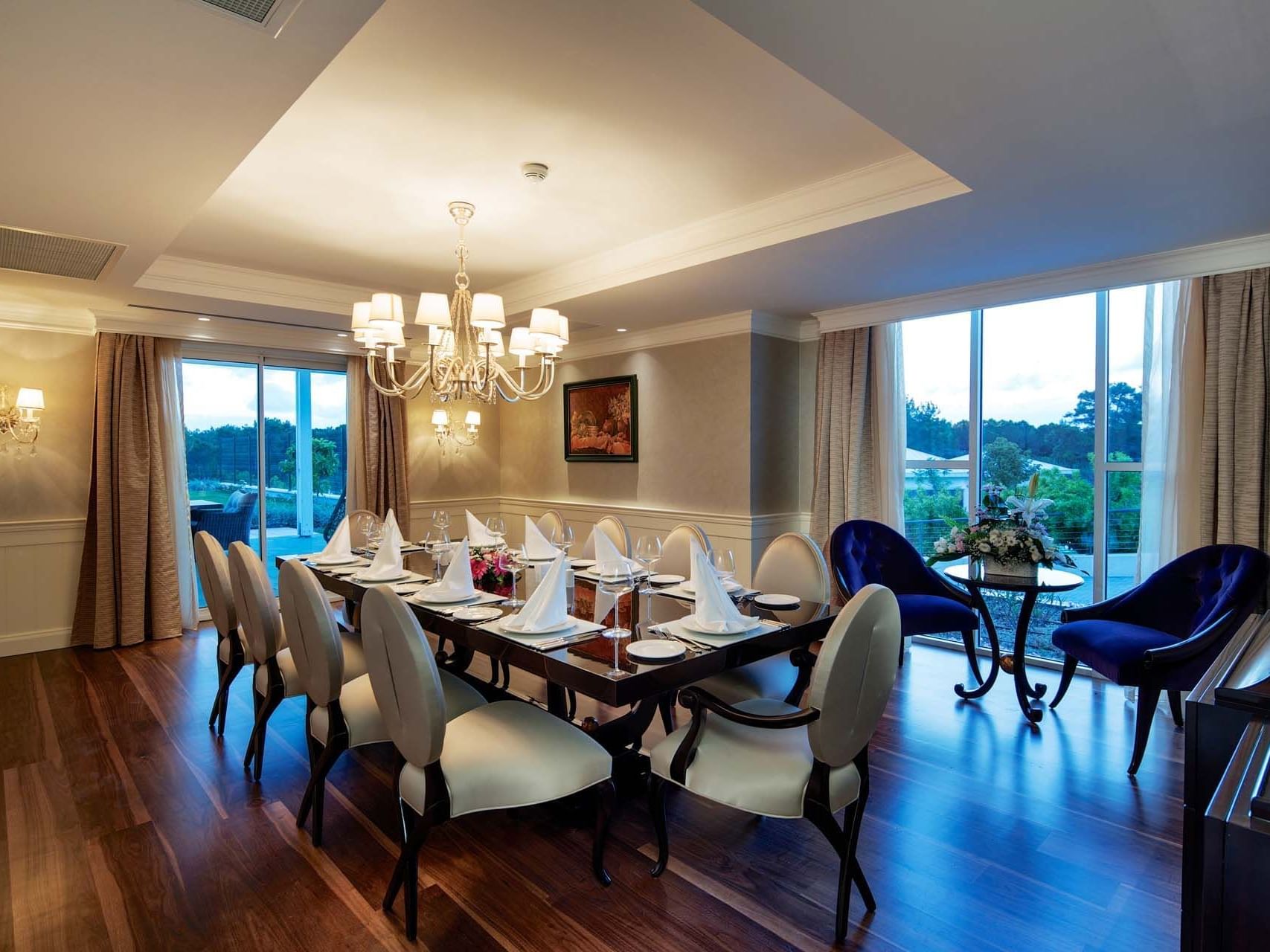 Elegant dining area with chandelier, set table, and a view through windows in a room at Titanic Deluxe Golf Belek