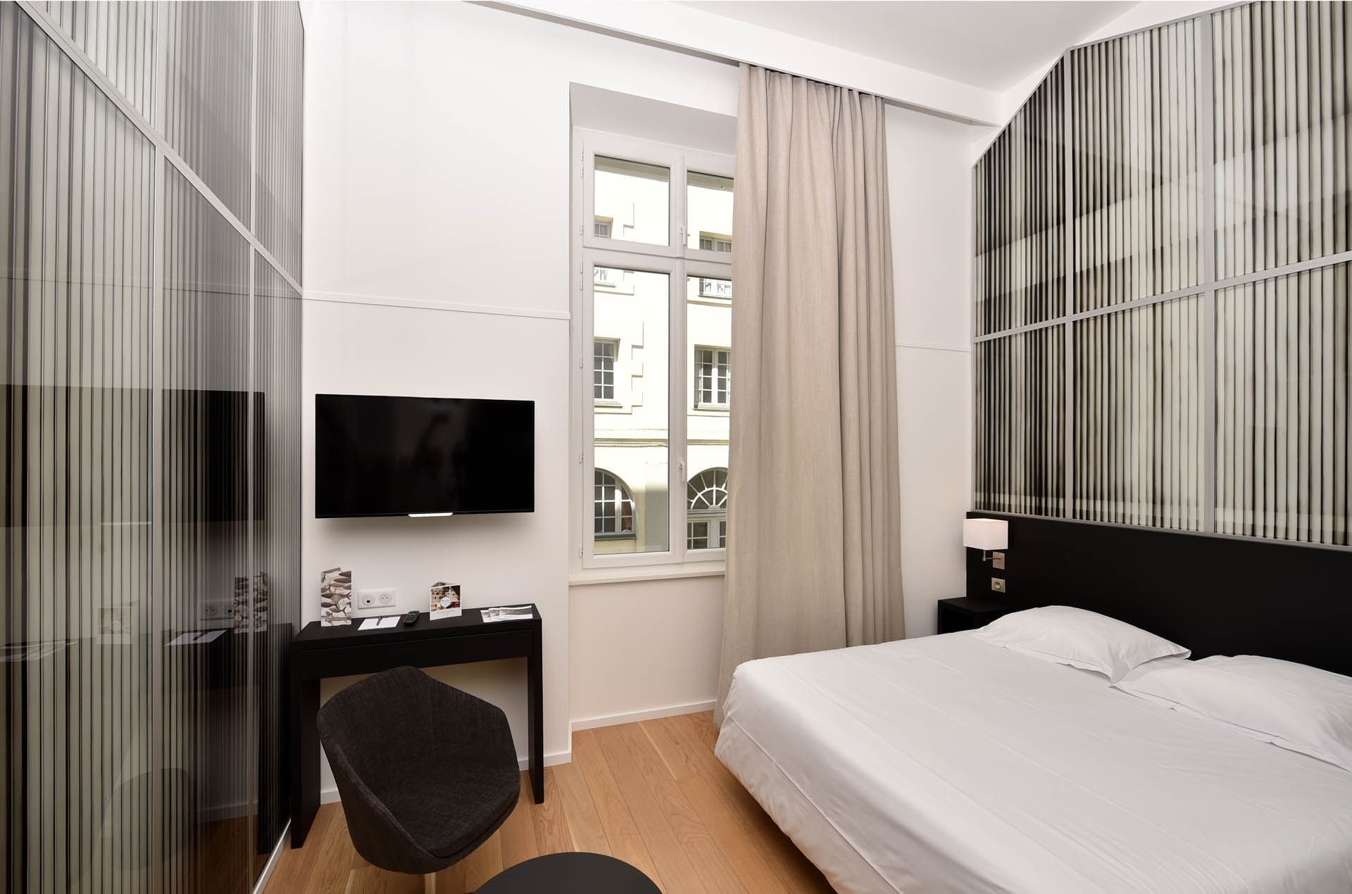 Lit king-size et télévision dans une chambre à Oceania Hôtel de France Nantes