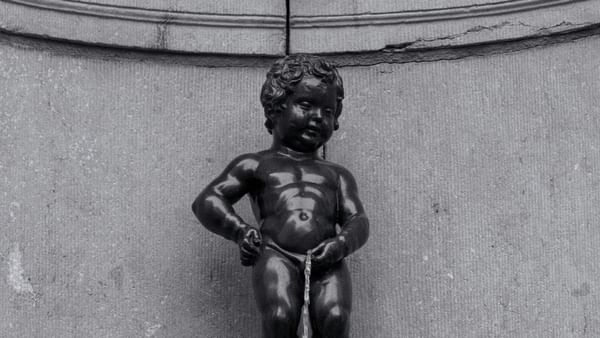 Black and white photo of the Manneken Pis statue by a stone wall under a ledge at Hotel Barsey by Warwick
