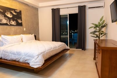 Two beds with wooden dresser and balcony seating area in Junior Suite King at Panama Hotel