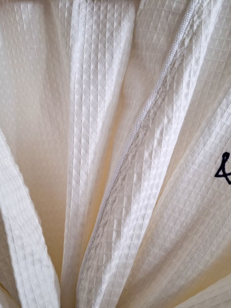 Close-up of a white waffle-weave robe with a black crown logo in Harbour Deluxe Balcony at Warwick Paradise Island Bahamas