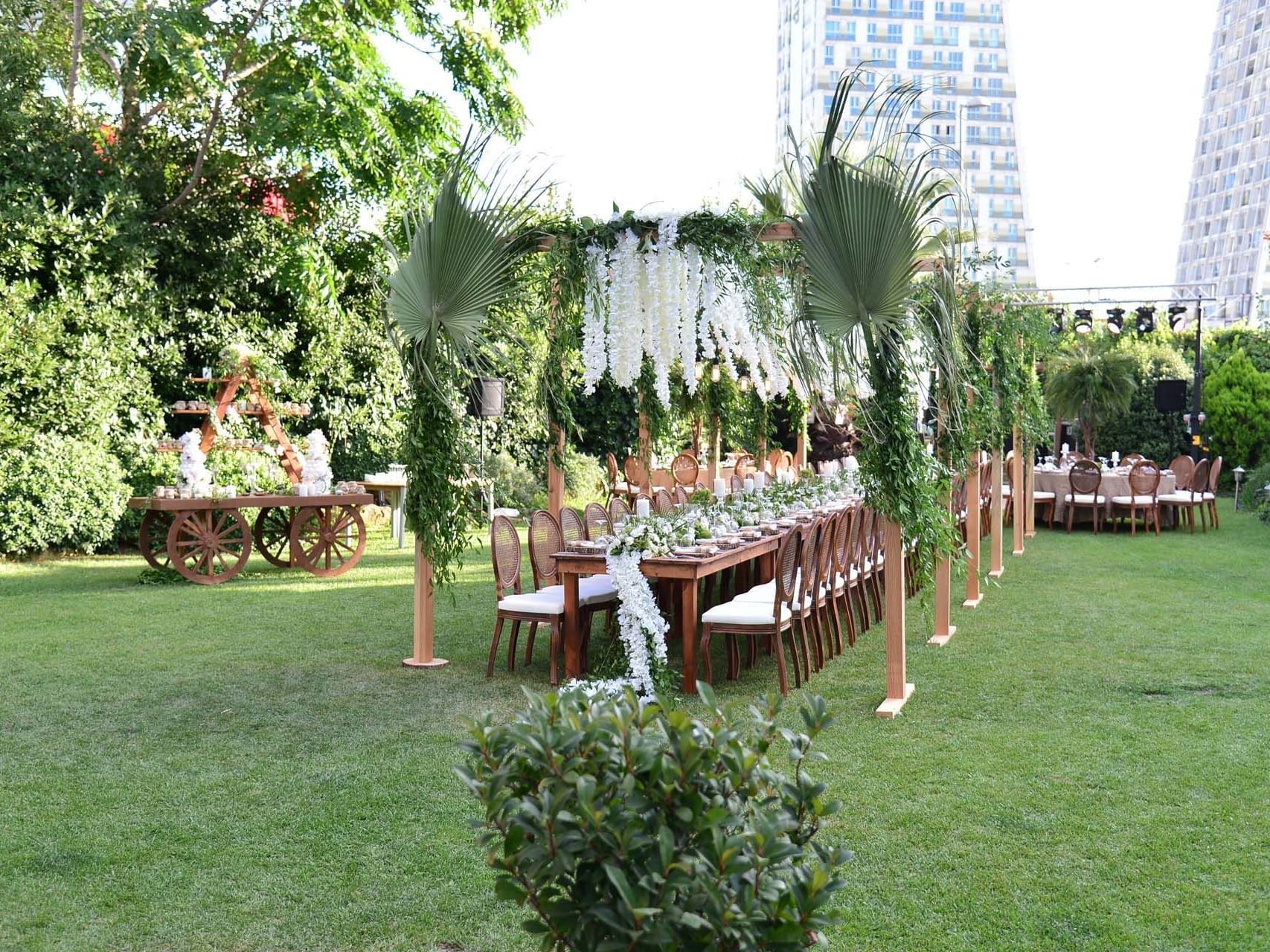 Titanic Business Kartal’da açık alanda, düğün için çiçeklerle süslenmiş uzun yemek masası ve sandalyelerle şık bir düzenleme.