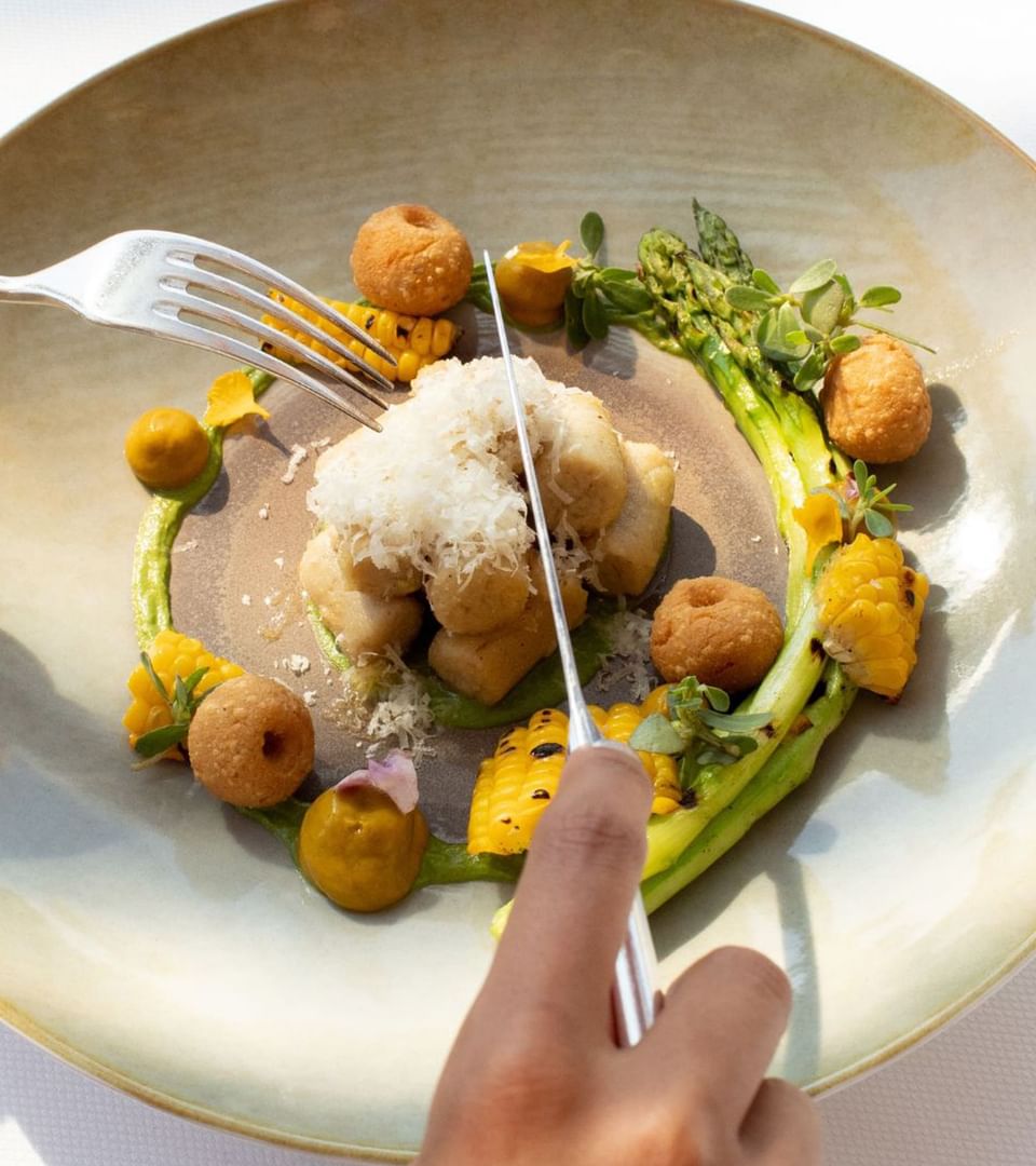 Gourmet gnocchi dish with cheese, corn, asparagus, and sauces, ready to be served at The Saujana Hotel Kuala Lumpur