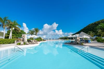 Piscine extérieure entourée de chaises longues et de palmiers au St. Martin Beach Resort, l'un des meilleurs complexes hôteliers de St.