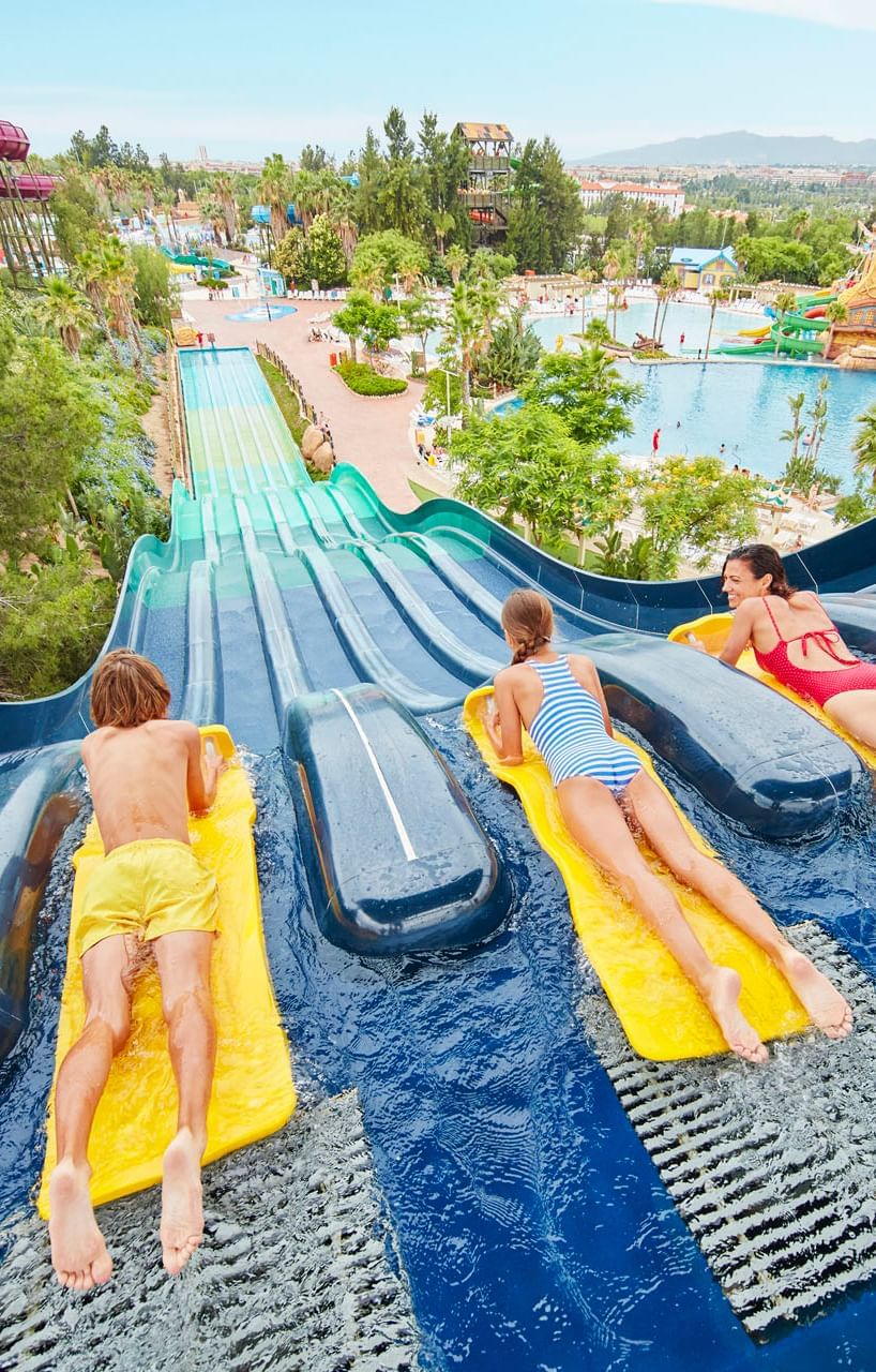 Niños deslizándose por toboganes de agua en Caribe Aquatic Park en un día soleado cerca de Ponient Hotels