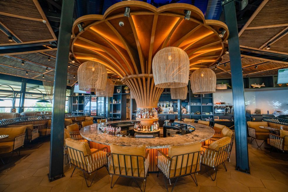 Barinterieur met een ronde marmeren toonbank en houten plafondaccent in het Breeze Restaurant bij Golden Rock Resort