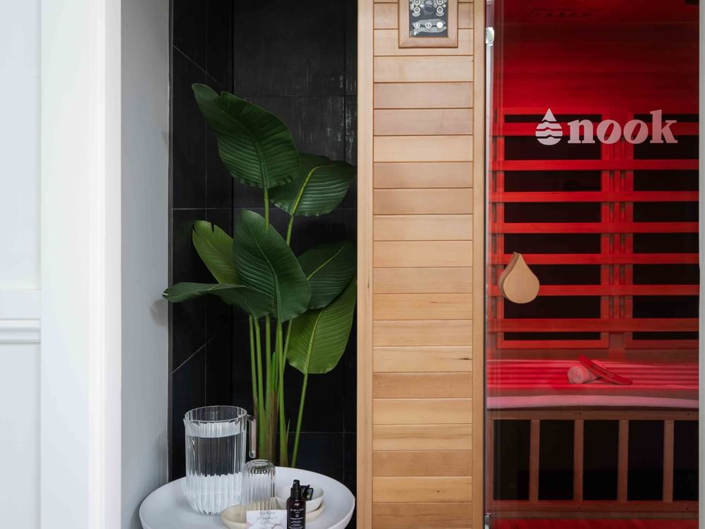 Wildfire Day Spa sauna with red light next to a black-tiled wall and green plant at Mercure Kooindah Waters