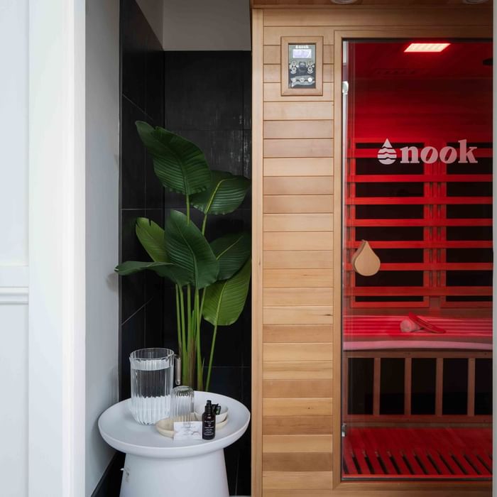 Wildfire Day Spa sauna with red light next to a black-tiled wall and green plant at Mercure Kooindah Waters