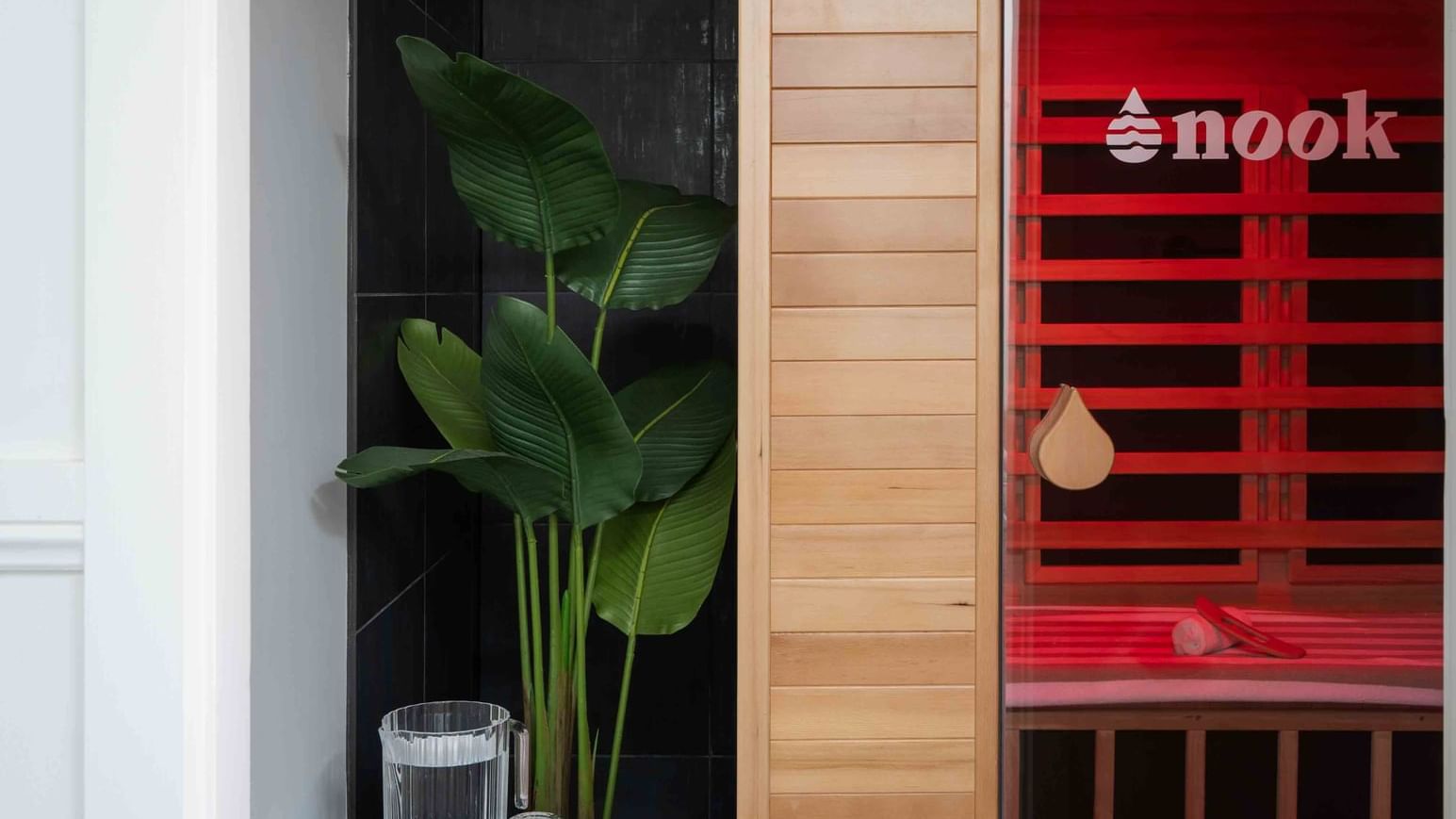 Wildfire Day Spa sauna with red light next to a black-tiled wall and green plant at Mercure Kooindah Waters