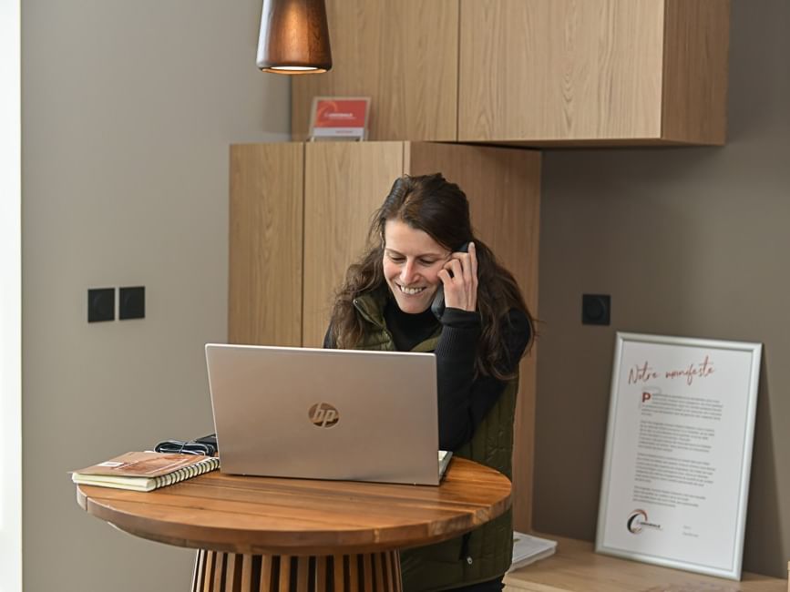 Femme heureuse au téléphone avec ordinateur portable à Hôtel Rivella.