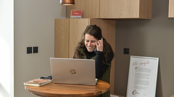Femme heureuse au téléphone avec ordinateur portable à Hôtel Rivella.