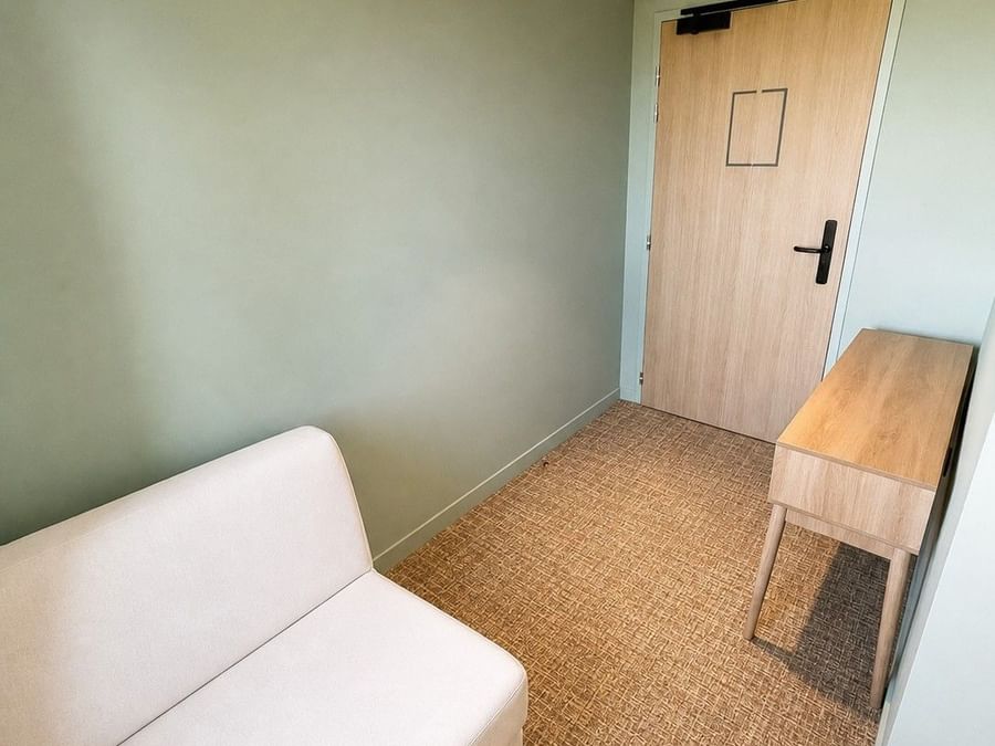Suite Junior avec canapé blanc et table en bois chez Osmo Hôtel à Chantepie