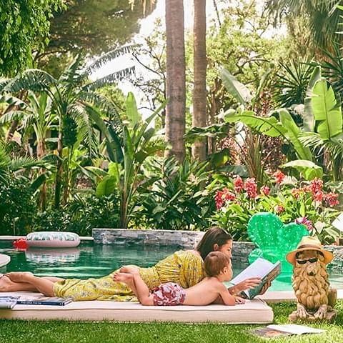 Lady & her child with a book laying by a pool at Marbella Club
