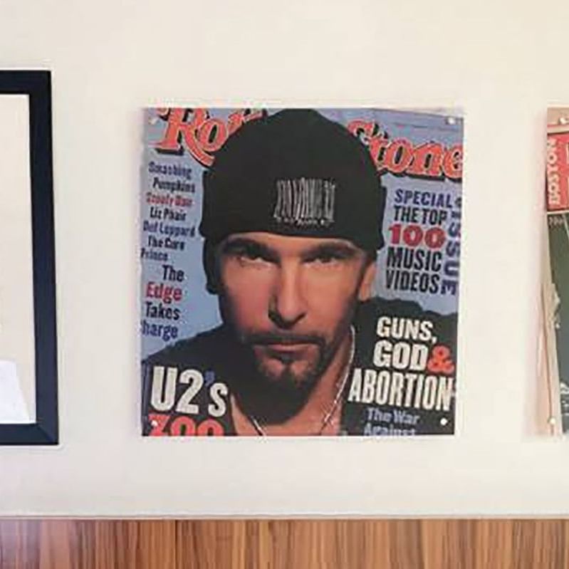 Framed photographs and vintage Rolling Stone magazine covers displayed on a white wall above wood paneling