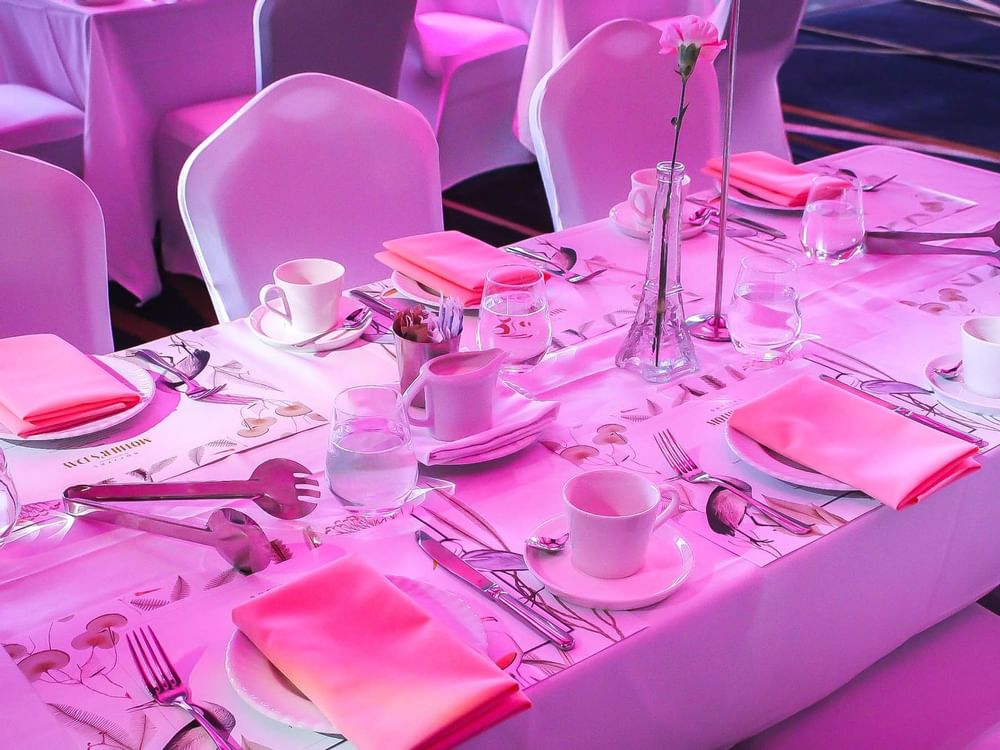 A beautifully arranged dinner table illuminated by soft pink lighting at Sofitel Brisbane Central