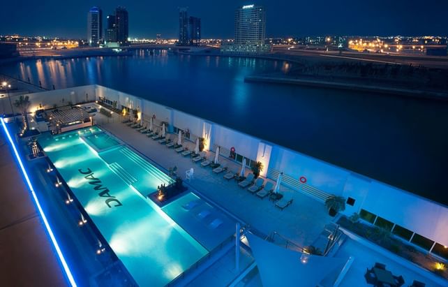Aerial view of an outdoor pool with attractive night city lights at DAMAC Maison Canal Views