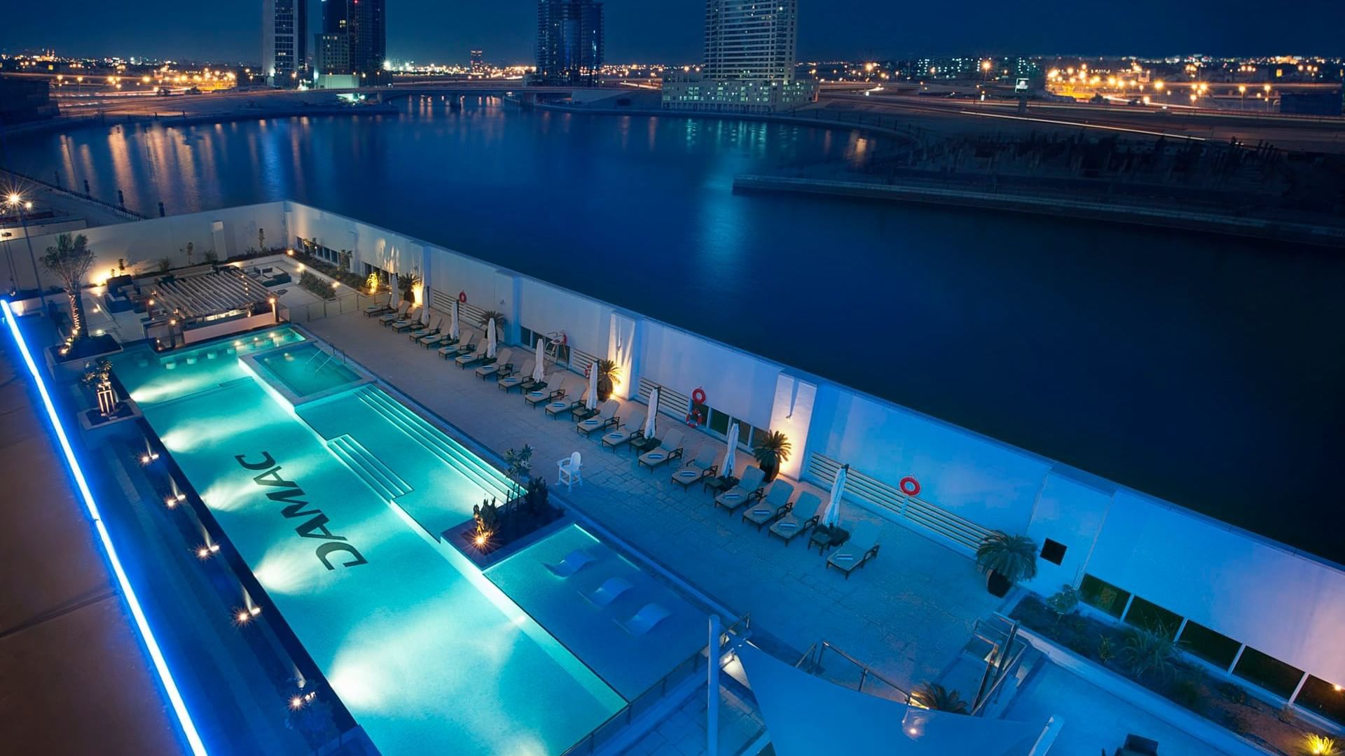 Aerial view of an outdoor pool with attractive night city lights at DAMAC Maison Canal Views