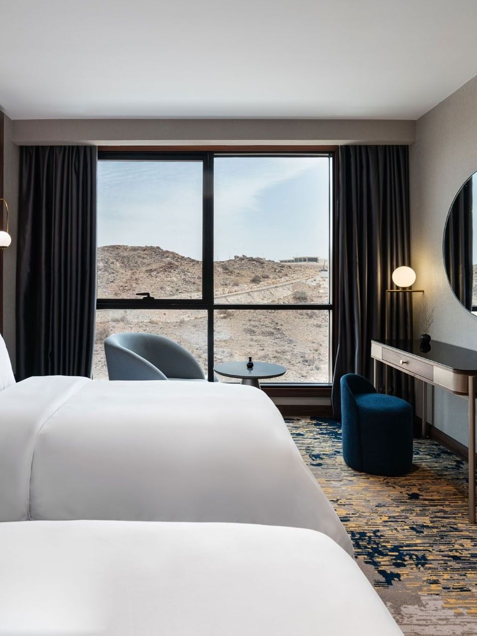 TV facing two beds with a work desk by the window in Royal Suite at Warwick Al Taif Hotel