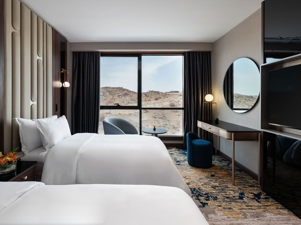 TV facing two beds with a work desk by the window in Royal Suite at Warwick Al Taif Hotel