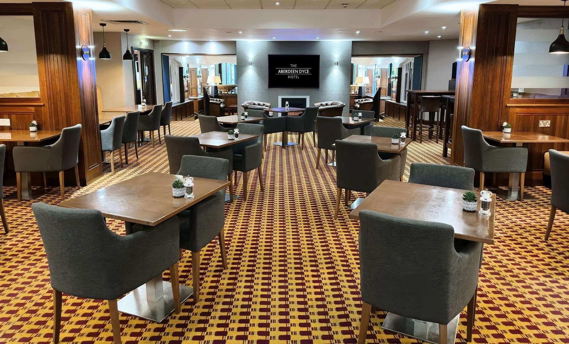Modern seating, wooden accents, and a well-lit dining area in Caskieben at The Aberdeen Dyce Hotel