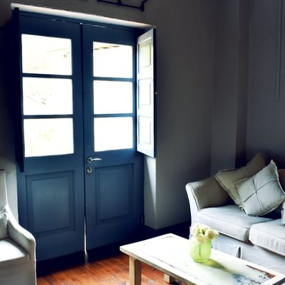 White sofa by a wooden coffee table under soft light by open blue doors in a suite at NOI Blend Colchagua