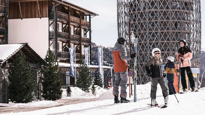 Eine Gruppe von Skifahrern steht auf einem schneebedeckten Gelände vor einem Gebäude.