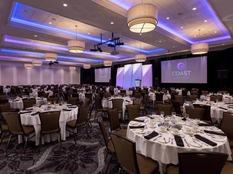Ballroom with round tables, chairs, stage, podium and presentation screen