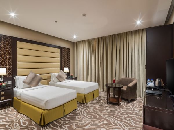 Two beds with armchair in Twin Deluxe at Naviti by Warwick Al Khobar