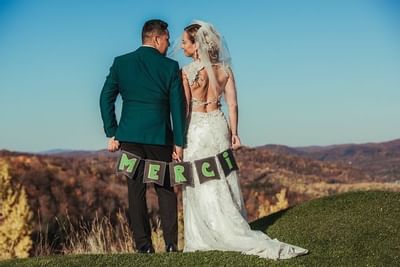 A wedded couple holding a Merci Poster at Hotel Mont Gabriel