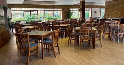 Well-lit dining area at Habitel Hotel Select with wooden tables, comfortable chairs and large windows in Zoe Restaurant