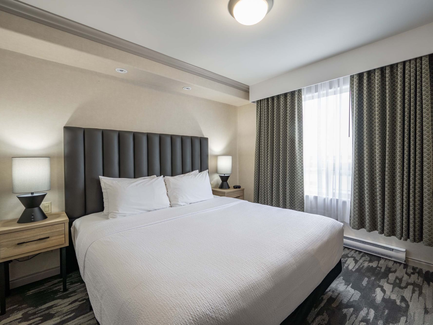 Bed with nightstand in Standard Suite, 1 King Bed, Sofa Bed, Kitchenette at Sandman Hotel & Suites Winnipeg Airport