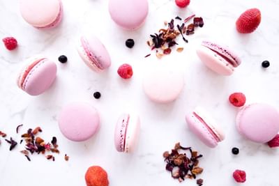 Flat lay of delicate pink macarons scattered with berries and dried petals in The Pastry Boutique at Park Hyatt Saigon