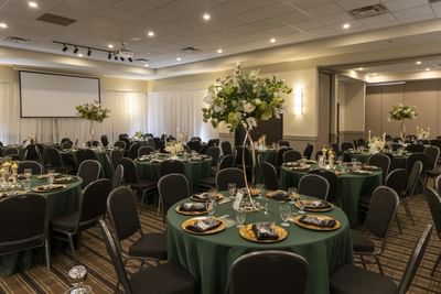 Floral centerpieces on round tables by black chairs in Sevogle Room at Rodd Miramichi River,a top choice for Miramichi events