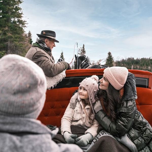 A family enjoying a ride in the winter at Falkensteiner Hotels & Residences