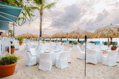 Beachside dining area with thatched umbrellas at Passions on the Beach